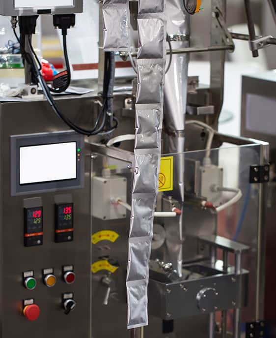 An automated machine fills and seals a bag with food.