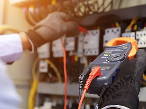 An individual uses an electrical meter to measure voltage.