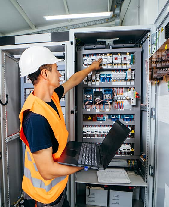 A man wearing a white shirt and orange vest holds a laptop, appearing attentive and ready to work on a task.