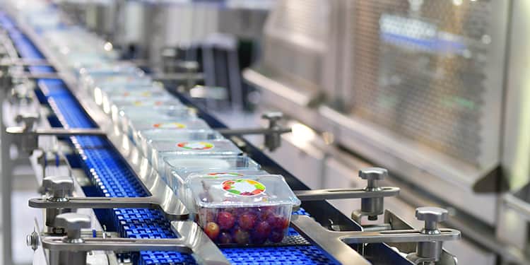 A conveyor belt transporting multiple plastic containers in a factory setting.