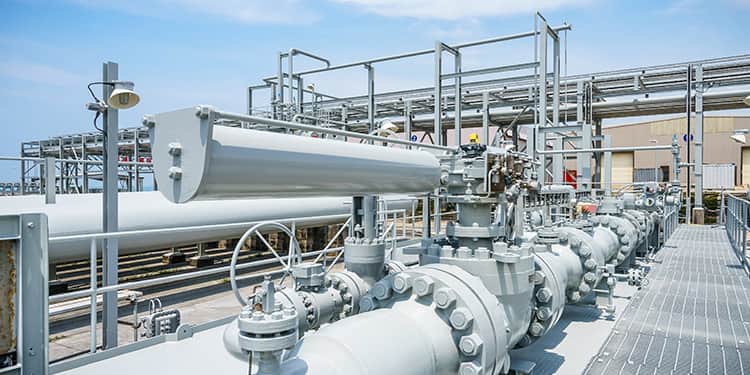 A large industrial pipe with multiple valves and connecting pipes situated on a raised platform.