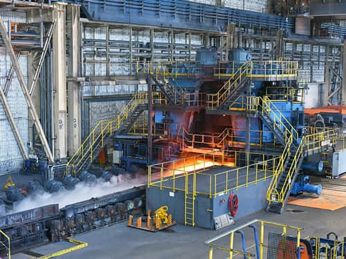 A large industrial factory with molten steel being poured into molds.