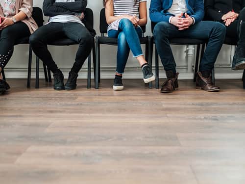 A group of people seated in a line on chairs.