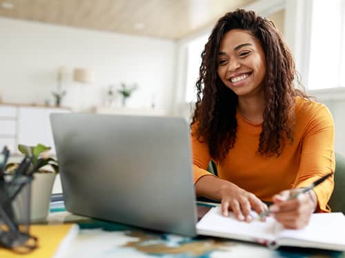 A woman with a bright smile engages with her laptop.